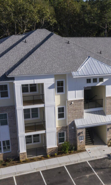 Aerial view of apartment complex with balconies overlooking parking lot