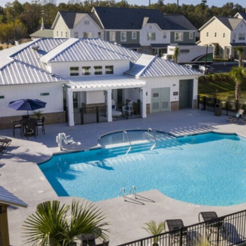 aerial shot of pool area with view of outdoor lounge area and half circle pool shape